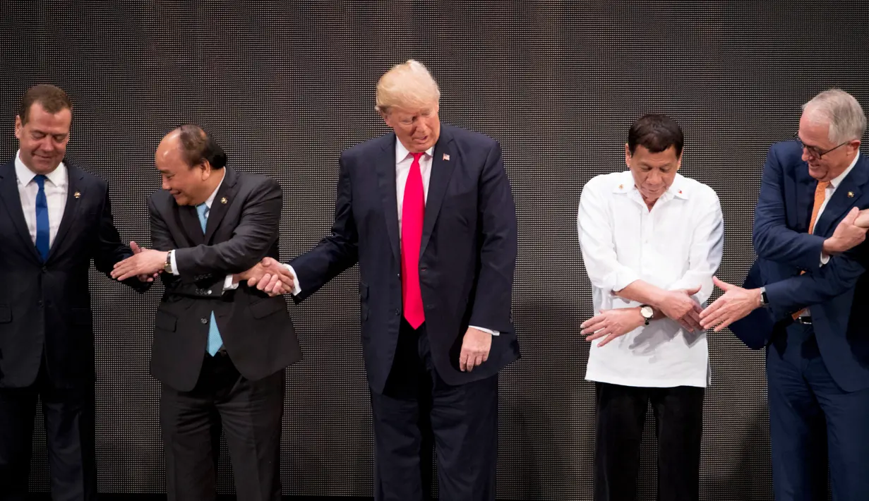 Presiden AS, Donald Trump menengok ke kanan dan ke kiri saat kebingungan melakukan salaman khas ASEAN pada upacara pembukaan KTT ASEAN di Manila, Filipina, Senin (13/11). Trump tampak kesulitan menempatkan tangannya. (AP/Andrew Harnik)