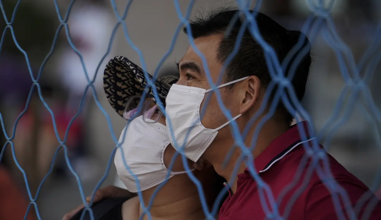 Orang tua yang mengenakan masker berjaga-jaga dari balik pagar saat para siswa memasuki sekolah untuk ujian masuk perguruan tinggi nasional China, atau dikenal gaokao, di Beijing, Selasa (7/6/2022). Tes tersebut menguji siswa dengan empat mata pelajaran, yakni matematika, bahasa Inggris, bahasa China, dan mipa atau soshum. 
(AP Photo/Andy Wong)