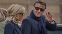 Presiden Prancis Emmanuel Macron melambai saat dia dan istrinya Brigitte Macron berjalan di sepanjang jembatan dengan latar belakang Istana Westminster di London pada 18 September 2022, menjelang pemakaman Ratu Elizabeth II. (HEIKO JUNGE / NTB / AFP)