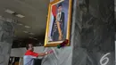Petugas membersihkan foto presiden Joko widodo yang baru dipasang di pilar Gedung Nusantara III Kompleks Parlemen Senayan, Selasa (23/12/2014). (Liputan6.com/Andrian M Tunay)