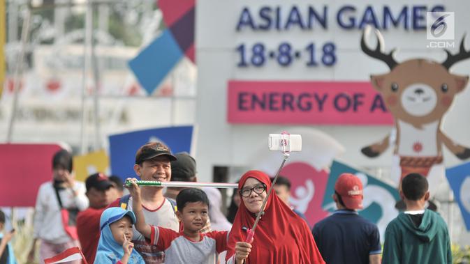 Warga berselfie saat menyaksikan lomba lari maraton putri Asian Games 2018 di kawasan MH Thamrin, Jakarta, Minggu (26/8). (Merdeka.com/Iqbal S. Nugroho)