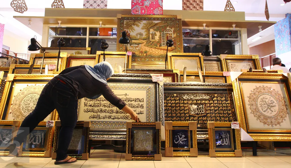 Pedagang tengah menata kaligrafi di pusat perbelanjaan di Jakarta, Rabu (22/6). Kaligrafi dijual dengan kisaran harga jual ratusan hingga puluhan juta rupiah tergantung motif dan tingkat kesulitan pembuatan. (Liputan6.com/Angga Yuniar)