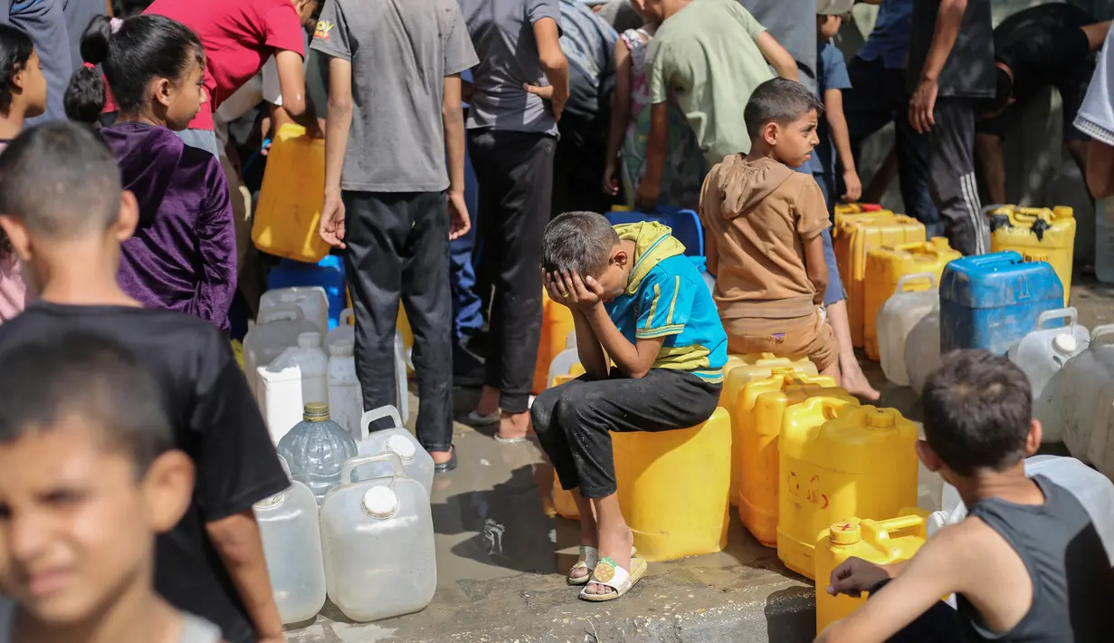 Anak-anak Palestina duduk di atas jeriken mereka sambil mengantre air di titik distribusi bantuan di kamp pengungsi Nuseirat, Jalur Gaza yang dikepung Israel pada 4 September 2025. (Eyad BABA/AFP)