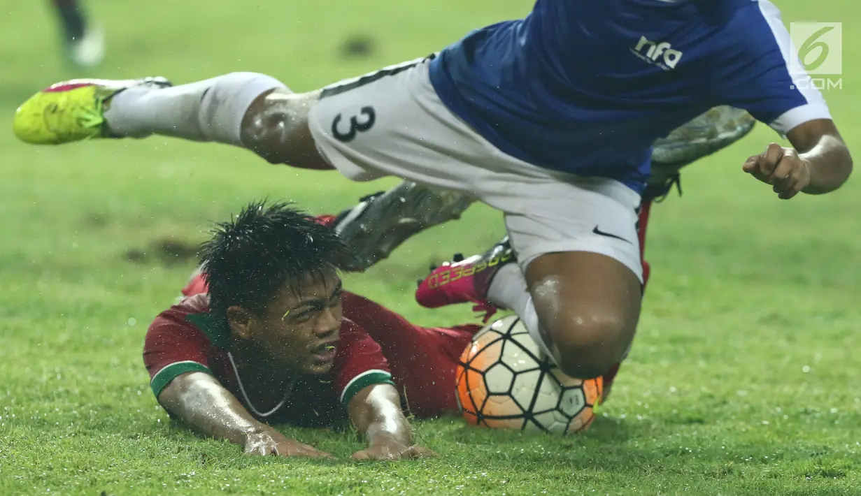 Gelandang Timnas Indonesia U-16, Kartika Vedayanto terjatuh saat berebut bola dengan pemain Singapura U-16, M Syafiq Bin Muhammad Sani di laga persahabatan di Stadion Wibawa Mukti, Kab Bekasi, Kamis (8/6). (Liputan6.com/Helmi Fithriansyah)