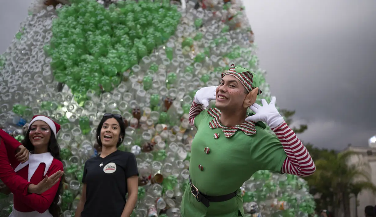Anak-anak muda berpakaian karakter Natal berpose untuk foto sebelum upacara penyalaan pohon Natal yang terbuat dari botol plastik daur ulang di Caracas, Venezuela, Selasa (13/12/2022). Pohon Natal yang dibuat dari sekitar 15.000 botol plastik daur ulang ini diinisiasi oleh organisasi nirlaba dan non-pemerintah Oko Spire dan kolaborator. (Yuri CORTEZ / AFP)