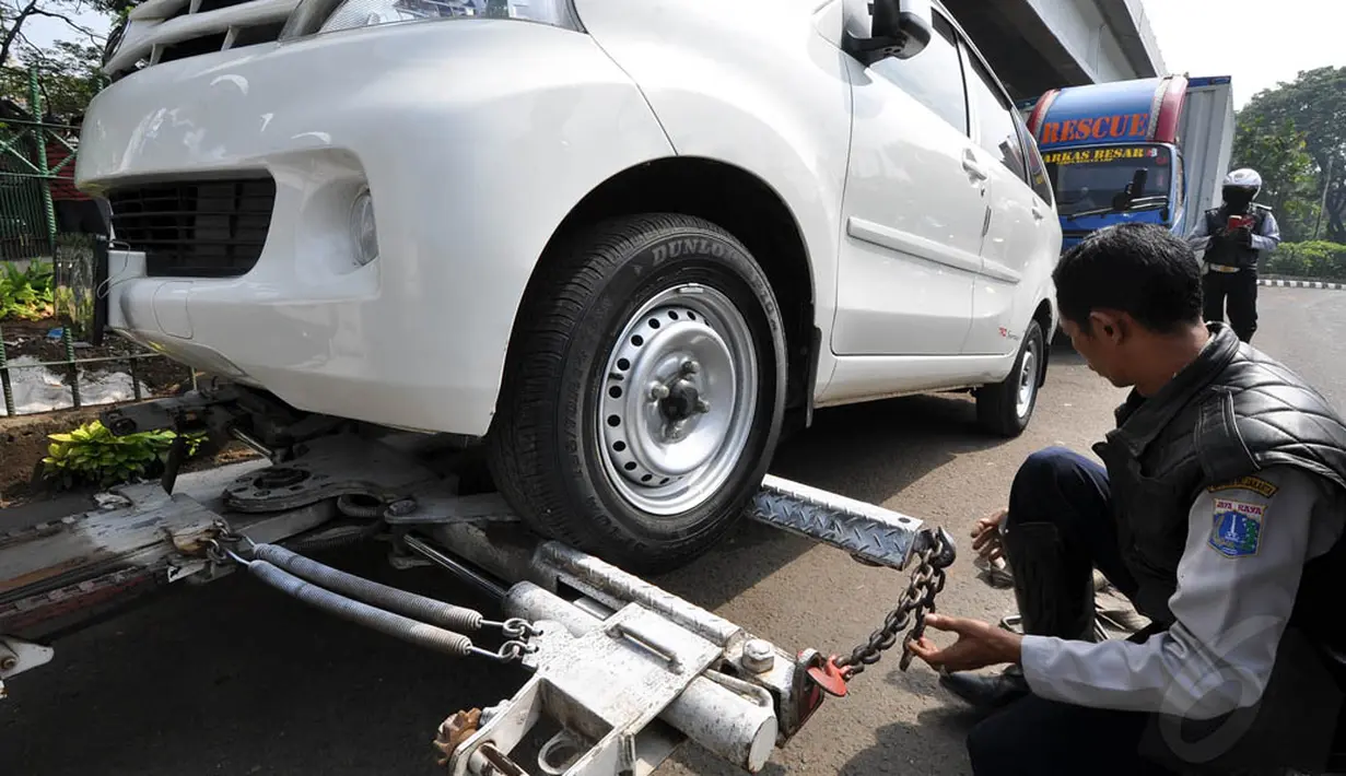 Sejumlah petugas menderek sebuah mobil di kawasan Casablanca, Jakarta, Rabu (12/11/2014). (Liputan6.com/Miftahul Hayat)