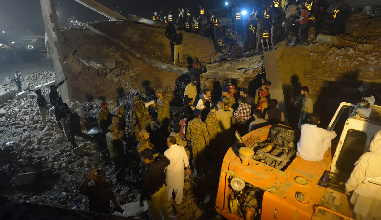 Tim SAR dibantu warga mencari korban di reruntuhan pabrik berlantai lima yang ambruk di Lahore, Pakistan Timur, Rabu (4/11) malam waktu setempat. Sedikitnya 16 orang tewas dan 40 luka-luka akibat kejadian tersebut. (AFP PHOTO/Arif Ali)