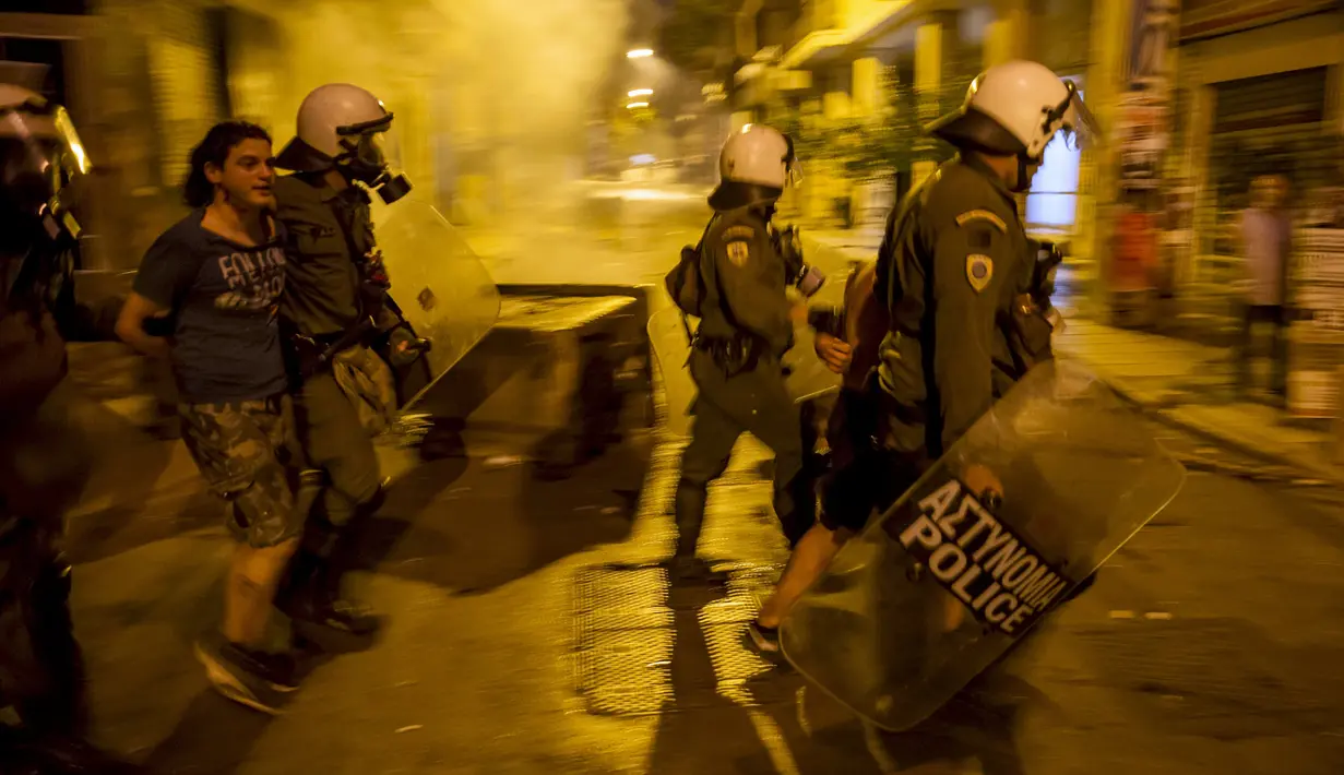 Polisi anti huru hara menahan seorang pemuda dalam bentrokan di pusat kota Athena, Yunani, (6/7/2015). Yunani Saat ini berstatus negara bangkrut, karena tidak bisa membayar utang-utangnya. (REUTERS/Marko Djurica)