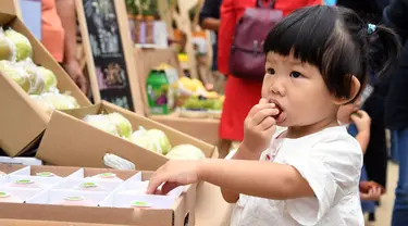 Seorang gadis kecil mencicipi produk-produk pertanian pada acara perayaan untuk menandai festival panen petani China di Distrik Pinggu, Beijing, ibu kota China, pada 24 September 2020. (Xinhua/Ren Chao)