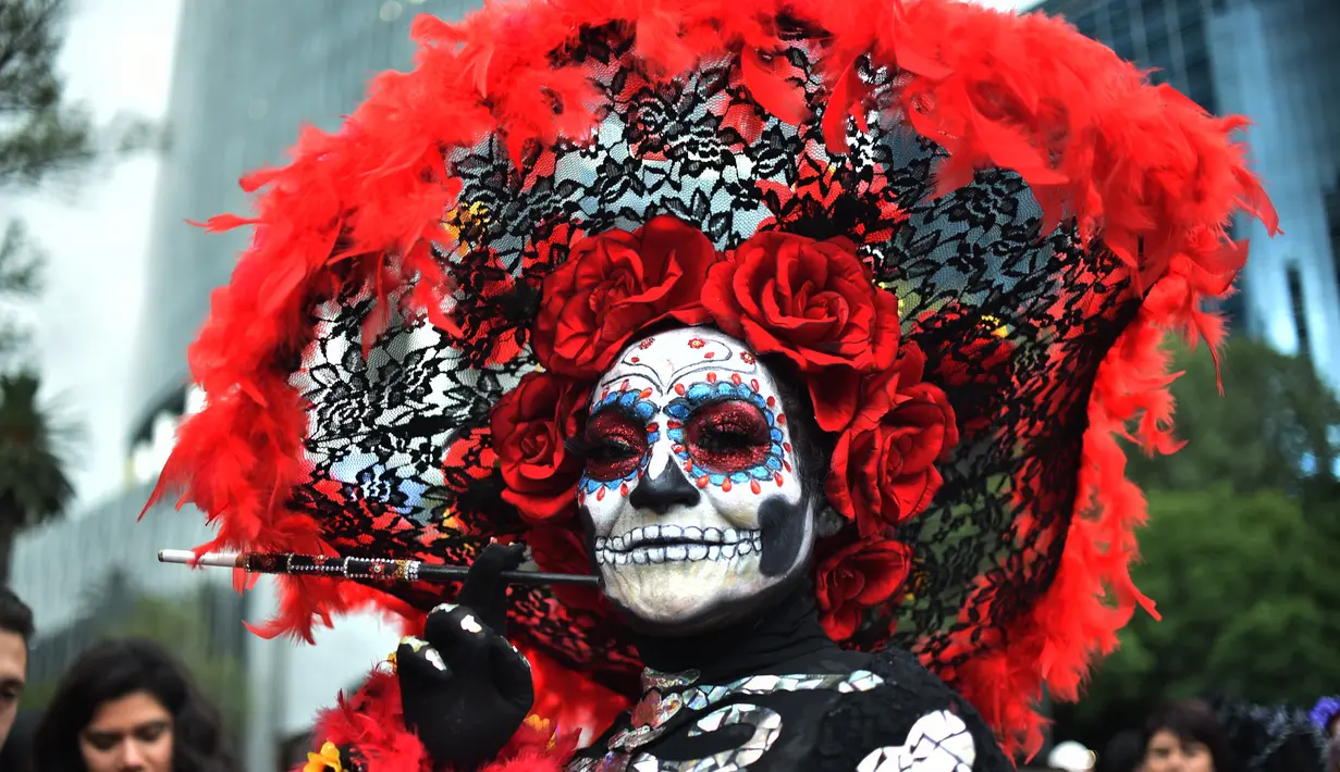 Seorang wanita berpakaian seperti "Catrina" ambil bagian dalam parade catrinas atau Hari Orang Mati di Reforma Avenue, Mexico City, 21 Oktober 2018. Hari kematian ini merupakan tradisi Halloween ala warga Hispanik di Meksiko. (RODRIGO ARANGUA/AFP)