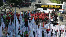 Bus Transjakarta melintas di depan massa buruh yang melakukan aksi peringatan May Day di Jalan MH Thamrin, Jakarta, Senin (1/5). Sambil meneriakkan aspirasinya, massa buruh mulai bergerak menuju Istana Negara. (Liputan6.com/Johan Tallo)