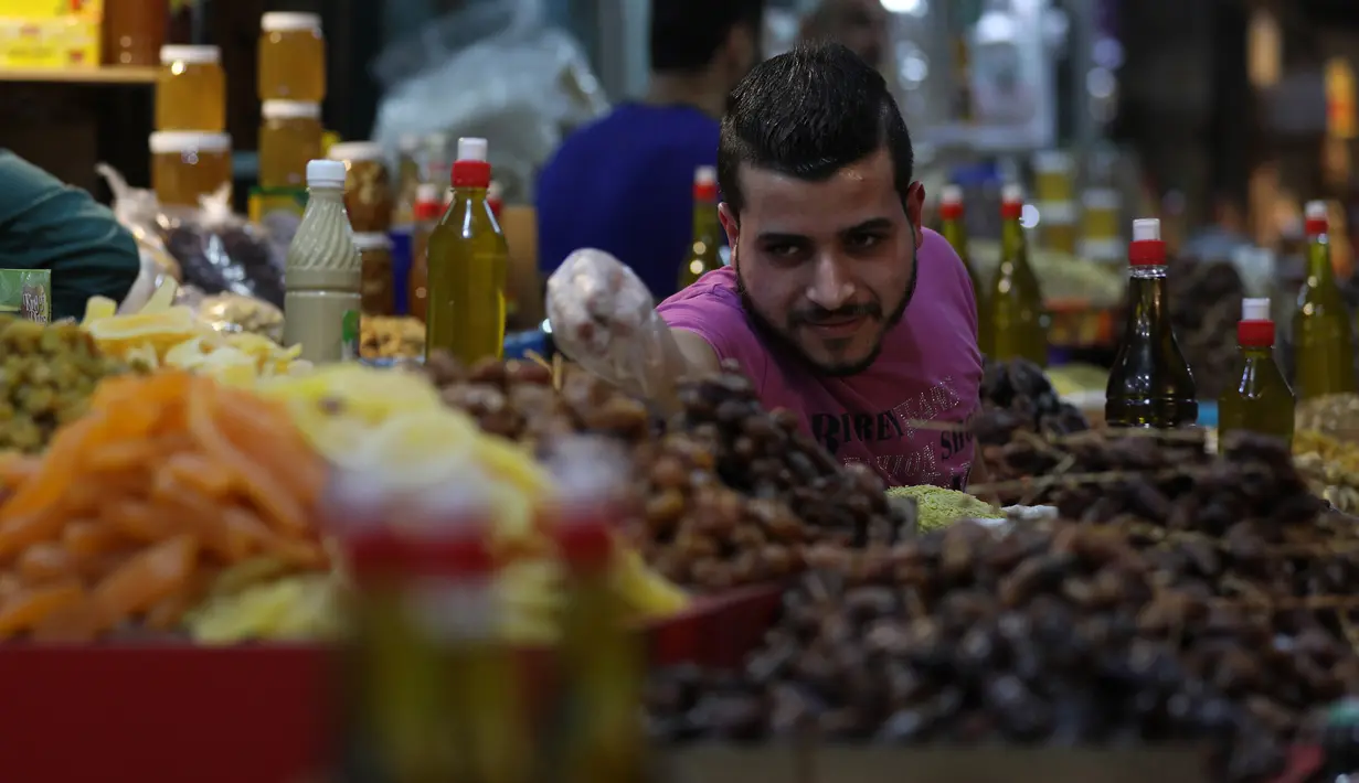 <p>Pedagang Palestina menjual kurma dan rempah-rempah di sebuah pasar menjelang bulan suci Ramadan di Gaza City pada 20 April 2020. Diberlakukannya larangan keluar rumah atau jam malam membuat miliar umat muslim di dunia akan menjalani Ramadan yang berbeda tidak seperti sebelumnya (Xinhua/Yasser Qudih)</p>