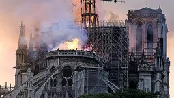 Api dan asap mengepul dari puncak menara Gereja Katedral Notre-Dame dalam kebakaran di pusat kota Paris, Prancis, pada Senin (15/4). Hingga kini belum diketahui pasti apa yang menjadi penyebab utama terbakarnya salah satu situs warisan dunia UNESCO tersebut. (AP Photo/Diana Ayanna)