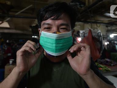 Pedagang mengenakan masker yang dibagikan petugas Polres Jakarta Timur selama sosialisasi di Pasar Palmeriam, Matraman, Selasa (9/2/2021). Kegiatan tersebut sebagai upaya meningkatkan kesadaran akan pentingnya penerapan protokol kesehatan untuk menekan penyebaran Covid-19. (merdeka.com/Imam Buhori)