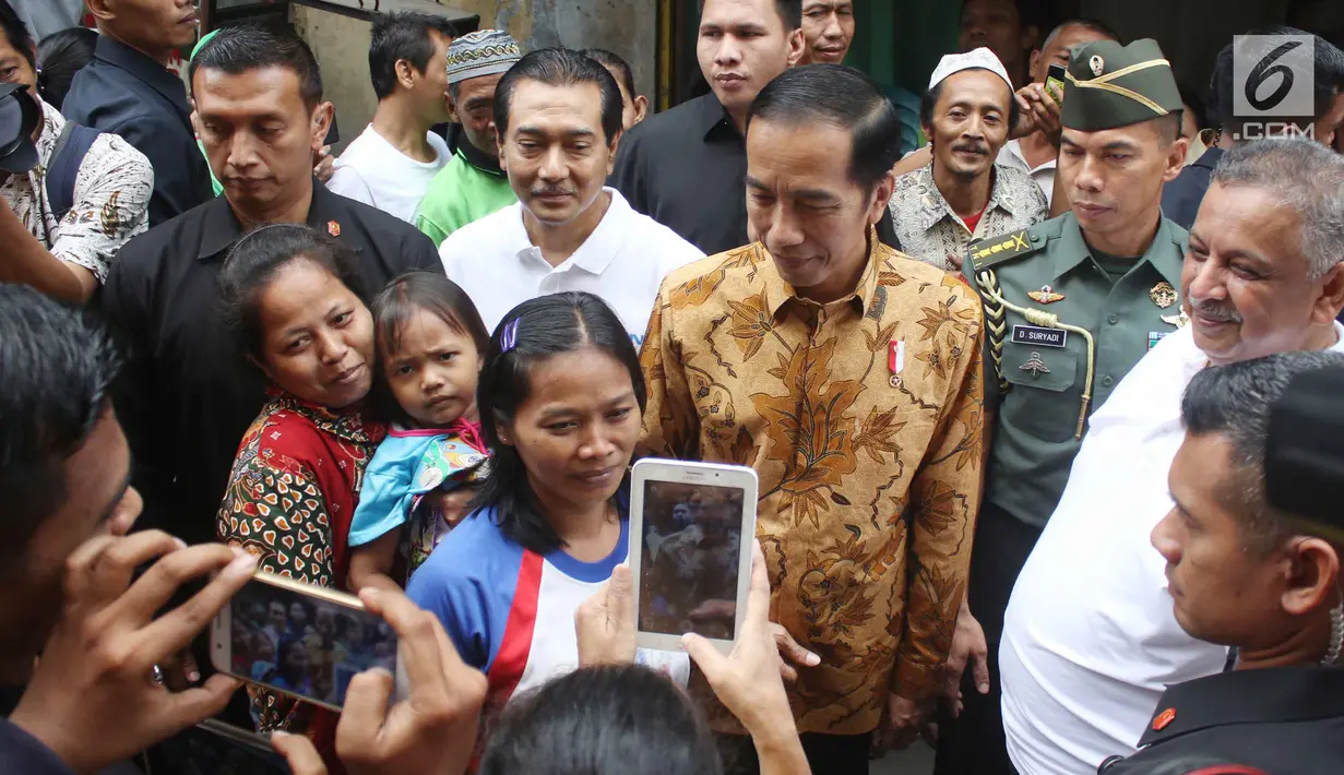 Warga berfoto bersama Presiden Jokowi saat menyaksikan pembagian paket Ramadan di wilayah Penjaringan, Jakarta, Selasa (13/6). Sebanyak 200.000 paket dibagikan gratis untuk meringankan beban masyarakat menjelang Idul Fitri. (Liputan6.com/Angga Yuniar)