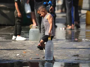 Seorang anak laki-laki Palestina membawa botol plastik besar berisi air di sebuah kamp pengungsi Nuseirat, yang terletak di Jalur Gaza tengah, pada 2 November 2025. Juru bicara Dana Anak-anak (UNICEF) Perserikatan Bangsa Bangsa (PBB), Tess Ingram mengungkap ada lebih dari satu juta anak di Jalur Gaza masih membutuhkan air bersih dan makanan. (EYAD BABA/AFP)
