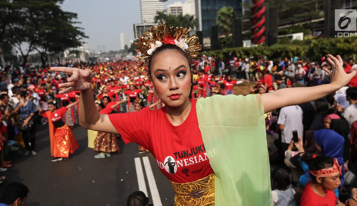 Seorang penari diikuti ribuan peserta membawakan Tari Puspanjali dari Bali saat CFD di Senayan, Jakarta, Minggu (12/8). Kegiatan ini digelar menyambut HUT Ke-73 RI dan Asian Games 2018. (Liputan6.com/Fery Pradolo)