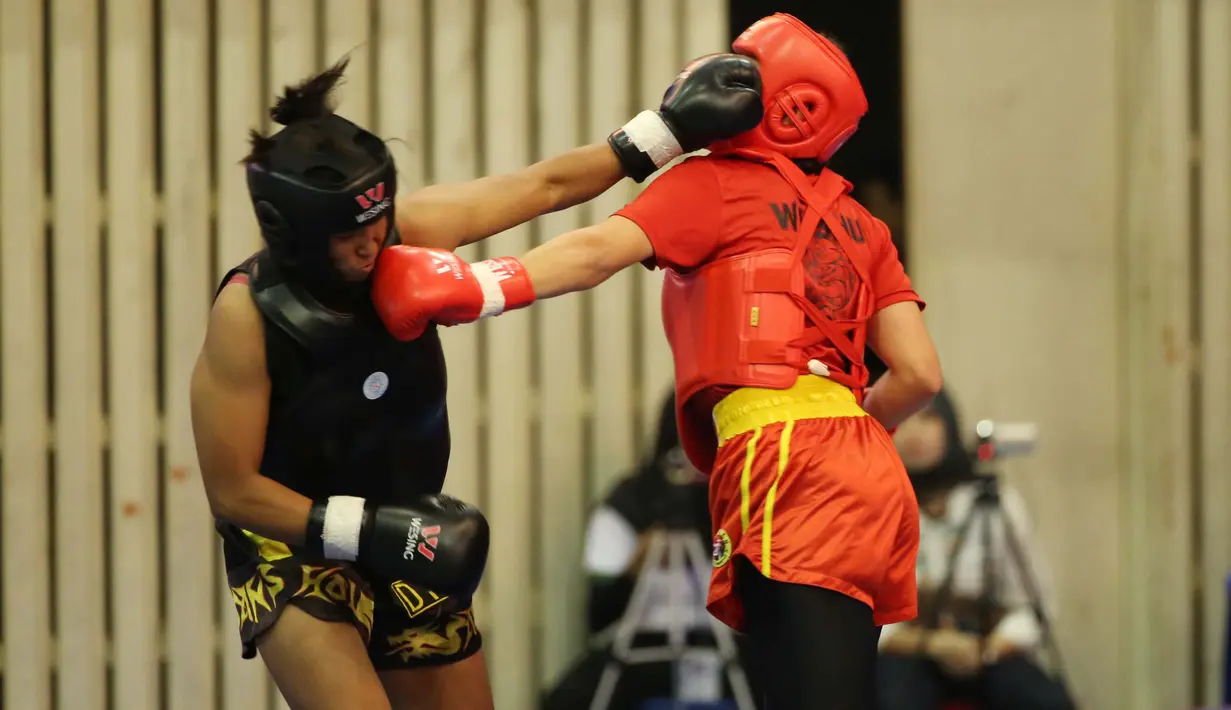 Atlet wushu Indonesia, Moria Manalu (kiri), memukul lawannya asal Turki, Nagihan Kalyoncu, di kelas Sanda Wanita 60 kg pada Kejuaraan Dunia Wushu 2015 di Istora Gelora Bung Karno, Senayan, Jakarta, Senin (16/11/2015). (Bola.com/Nicklas Hanoatubun)