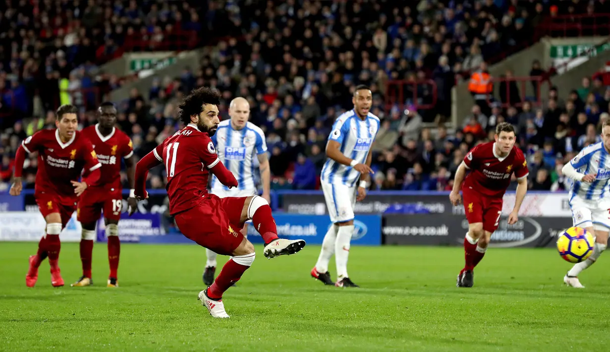 Pemain Liverpool, Mohamed Salah mencetak gol ke gawang Huddersfield Town lewat titik putih pada pertandingan pekan ke-25 Premier League di John Smith's Stadium, Selasa (30/1). Liverpool menghempaskan Huddersfield Town 3-0. (Martin Rickett/PA via AP)