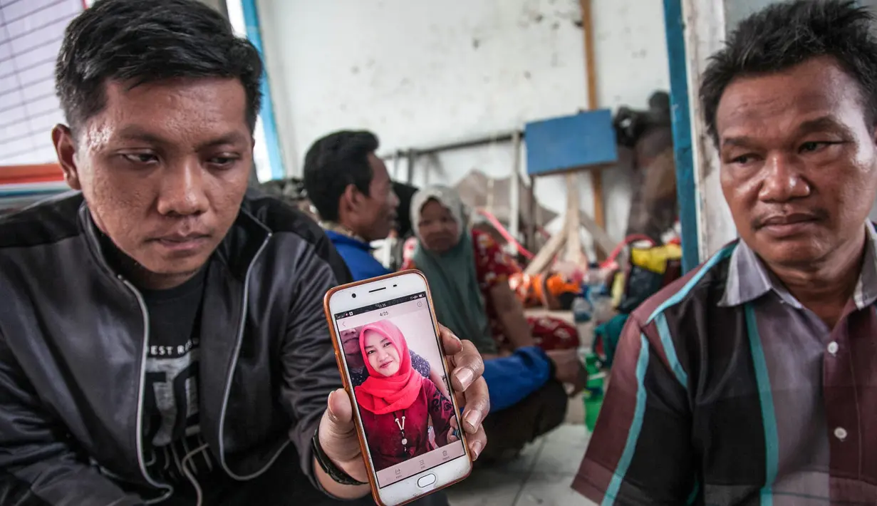 Keluarga korban kapal tenggelam KM Sinar Bangun menunjukkan foto anggota keluarganya di pelabuhan feri Danau Toba, Sumatera Utara, Rabu (20/6) . Foto keluarga yang dilaporkan hilang itu untuk mempermudah proses pendataan. (AFP PHOTO/IVAN DAMANIK)