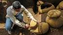 Pekerja mengamati tembikar berusia lebih dari 1.200 tahun yang ditemukan di lokasi pembangunan Stadion Bisbol Nasional yang baru di Managua, Nikaragua, Selasa (20/6). Barang-barang yang ditemukan akan dipamerkan di Museum Budaya Nasional. (INTI OCON/AFP)