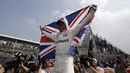 Gaya selebrasi Lewis Hamilton membentangkan bendera Inggris setelah memastikan diri meraih meraih gelar juara dunia F1 2017 di Hermanos Rodriguez racetrack, Mexico City, (29/10/20170). Hamilton finis kedelapan pada balapan tersebut. (AP/Moises Castillo)