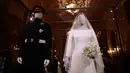 Gaun pernikahan Meghan Markle dan Pangeran Harry ditampilkan pada pameran A Royal Wedding di Kastil Windsor, London, 25 Oktober 2018. Gaun yang dikenakan Meghan, dipajang di kotak kaca besar di samping kostum pernikahan Pangeran Harry. (AP/Matt Dunham)