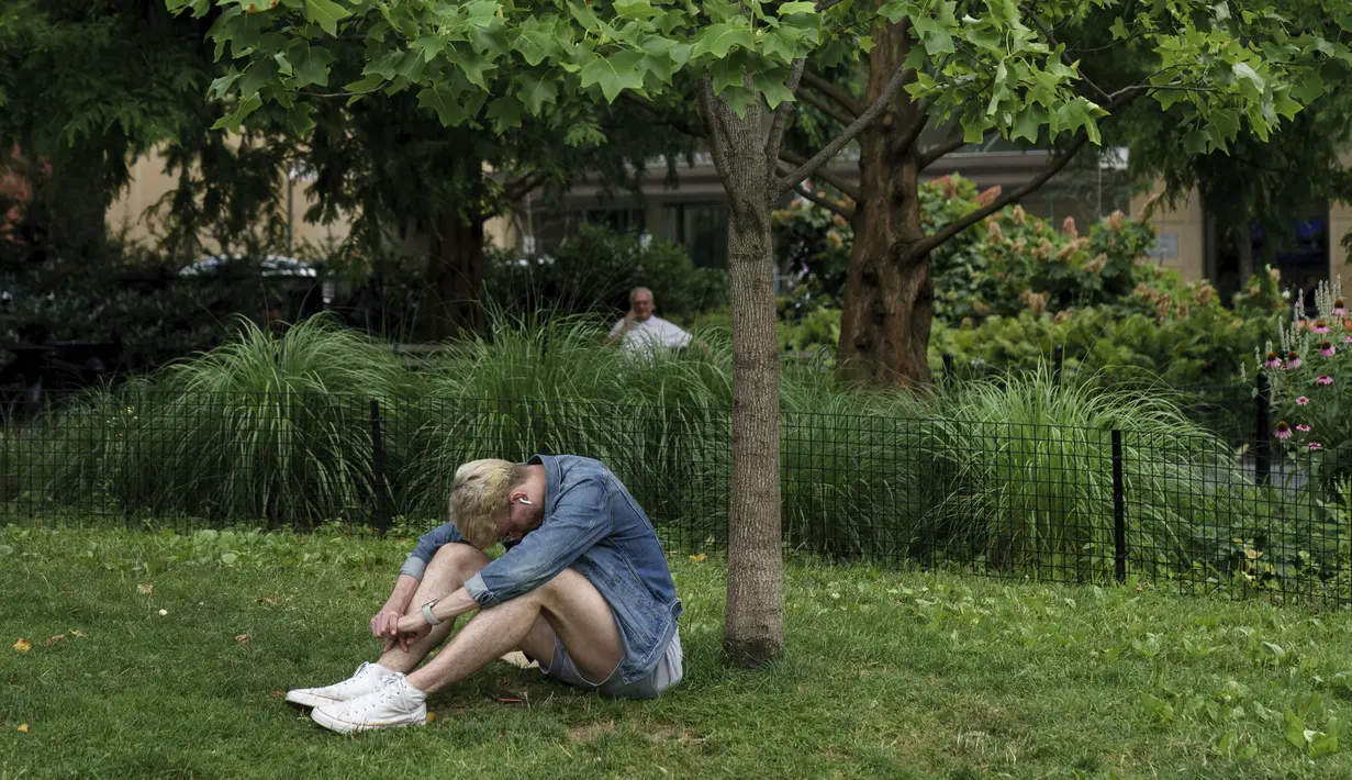 Seorang pria duduk di tempat teduh saat siang hari yang panas di Washington Square Park di New York City (17/7/2019). Panas terik bergerak ke daerah Kota New York, dengan suhu yang diperkirakan akan mencapai 100 derajat pada akhir pekan ini.  (AFP Photo/Drew Angerer)