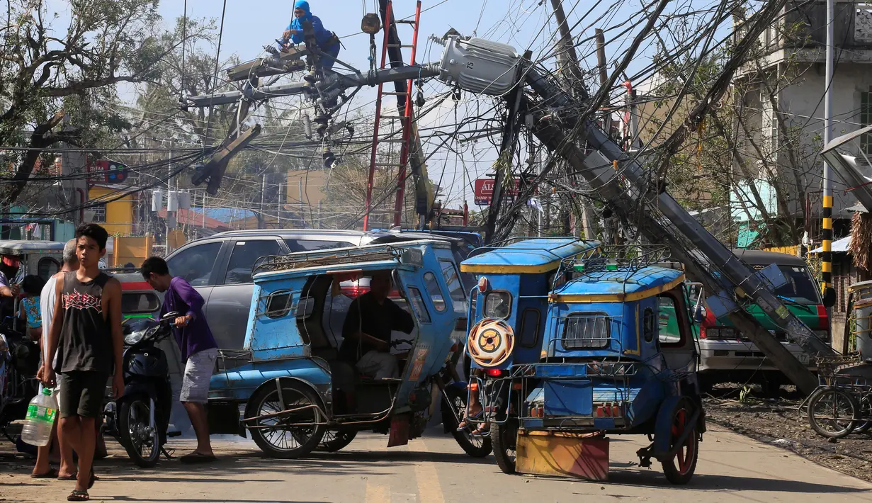 Pekerja memperbaiki tiang listrik yang roboh setelah dihantam Topan Nock-ten di Kota Iriga Camarines Sur, Filipina tengah (27/12). Topan Nock-Ten dilaporkan memutus listrik di lima provinsi saat puncak perayaan Natal. (REUTERS/Romeo Ranoco)