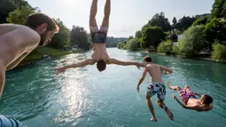 Para pemuda melompat ke Sungai Aare di Bern, Swiss, 21 Juni 2017. Selain panjang dan luas, Sungai Aare juga memiliki kedalaman mencapai 200 meter yang berlokasi dekat Meiringen. (Fabrice COFFRINI/AFP)