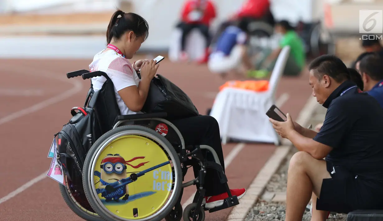 Atlet dan official tim China beraktivitas dengan ponsel mereka di kawasan Stadion Madya Kompleks Gelora Bung Karno, Jakarta, Kamis (11/10). Berbagai aktivitas dilakukan para atlet para atletik di luar arena. (Liputan6.com/Helmi Fithriansyah)