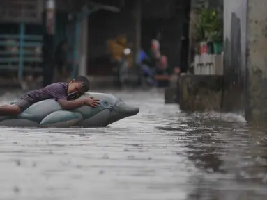 Seorang anak bermain saat banjir menggenangi kawasan Pasar Buncit, Jakarta Selatan, Selasa (9/2/2016). Banjir menggenangi kawasan tersebut hingga setinggi 100 cm akibat luapan Kali Kemang. (Liputan6.com/Gempur M Surya)