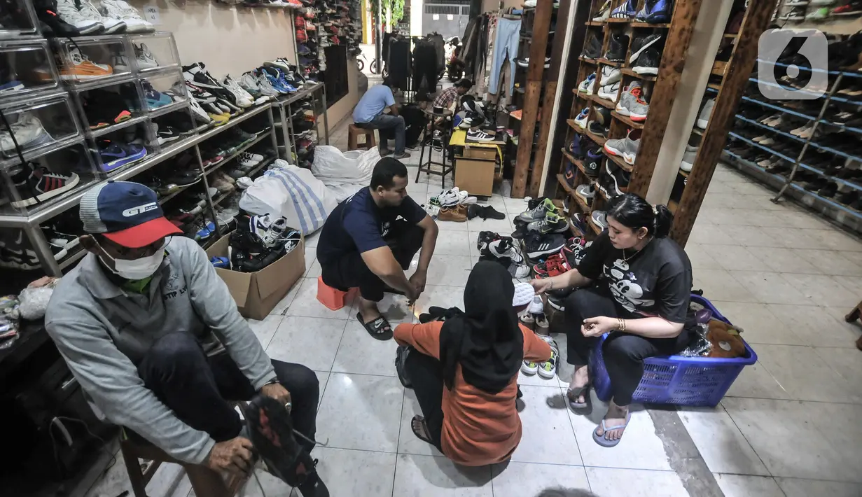 Calon pembeli saat menjajal seatu impor bekas di toko Second BJR, Kali Baru Timur, Cilincing, Jakarta Utara, Rabu (1/6/2022). Harga sepatu impor bekas mulai dijual oleh Bajuri kisaran Rp250 ribu hingga Rp7 juta per pasang. (merdeka.com/Iqbal S. Nugroho)