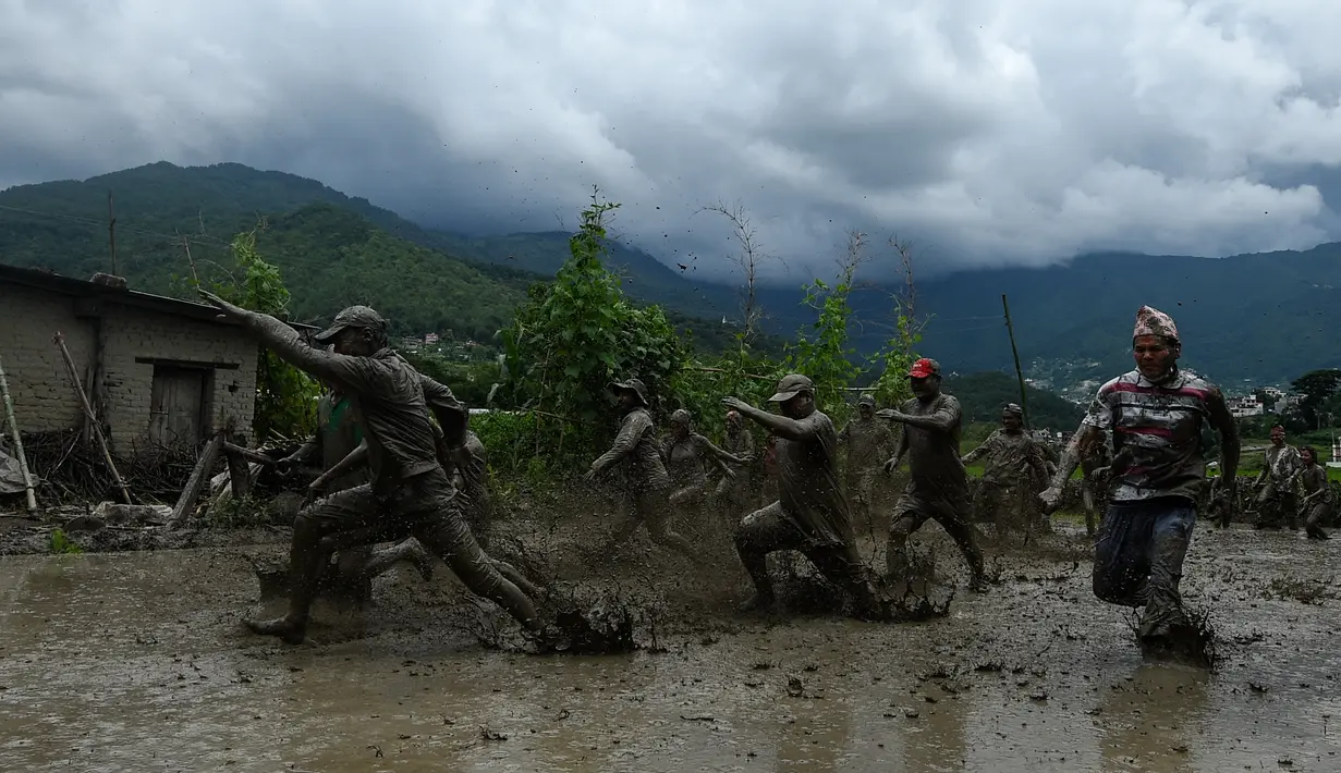 Para petani berlumur lumpur saat bermain pada Hari Padi Nasional di sawah Desa Tokha, Kathmandu, Nepal, Senin (29/6/2020). Para petani di Nepal merayakan Hari Padi Nasional sebagai musim tanam padi tahunan dimulai. (PRAKASH MATHEMA/AFP)
