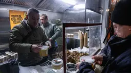 Di Kyiv, pemadaman listrik menyebabkan terhentinya sistem pemanas sentral dan air bersih bagi ribuan gedung apartemen. Tampak dalam foto, para veteran the 3rd Separate Assault Brigade Angkatan Bersenjata Ukraina menyajikan makanan panas gratis bagi orang-orang di lingkungan perumahan yang rumahnya tanpa listrik setelah serangan udara Rusia berulang kali terhadap sektor energi negara itu di Kyiv, Selasa 27 Januari 2026. (AP Photo/Danylo Antoniuk)