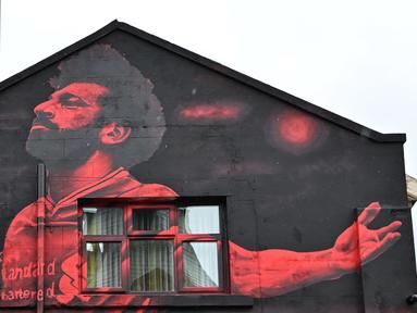 Mural seniman Inggris, John Culshaw yang menggambarkan pesepak bola Mesir Mohamed Salah dilukis di fasad bangunan dekat Stadion Anfield, di Liverpool, Rabu (30/3/2022). Mohamed Salah tidak diragukan lagi, adalah salah satu pemain terhebat yang pernah mengenakan seragam Liverpool. (Paul ELLIS / AFP)