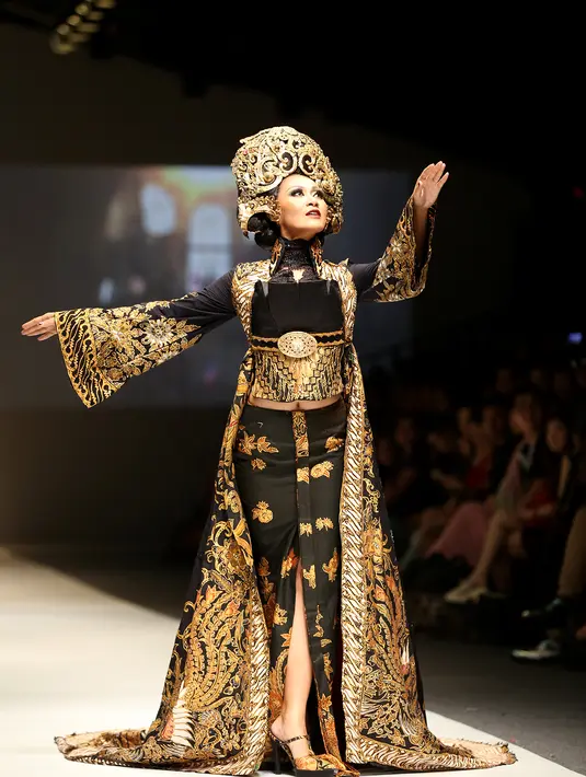 Rancangan glamor yang mengusung warna hitam dan emas ini menjadi salah satu bentuk representasi Anne Avantie atas keberagaman etnis di Semarang. Busana panjang mewah ini pun menyapu lantai sebagai transformasi kebaya modern. (Andy Masela/Bintang.com)