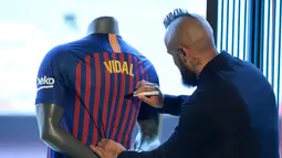 Pemain baru Barcelona, Arturo Vidal menandatangani jersey dalam presentasi resminya di Stadion Camp Nou, Barcelona, Spanyol, Senin (6/8). (Josep LAGO/AFP)