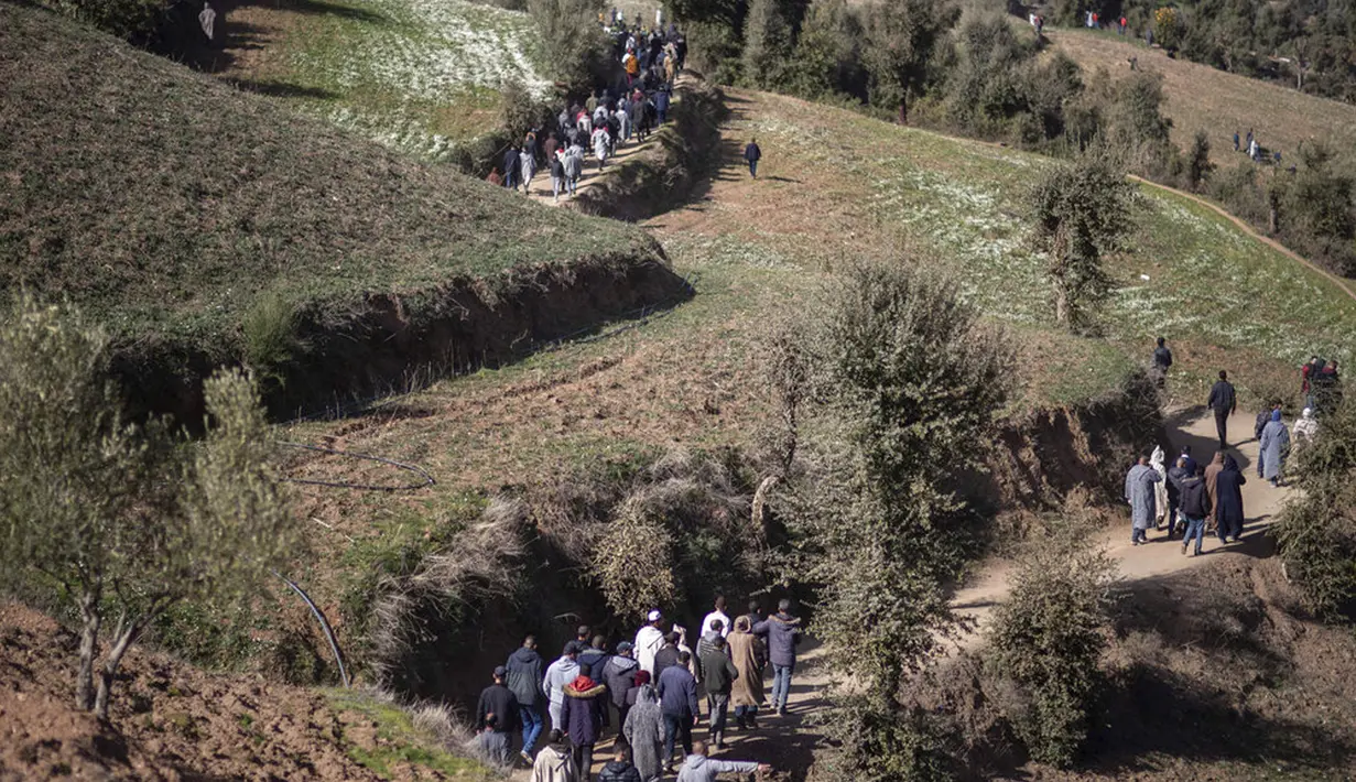 Orang-orang berjalan menuruni bukit saat mereka menghadiri pemakaman Rayan Oram (5) di Desa Ighran, Provinsi Chefchaouen, Maroko, 7 Februari 2022. Rayan Oram meninggal setelah terjebak selama lima hari dalam sumur kering sedalam 32 meter. (AP Photo/Mosa'ab Elshamy)