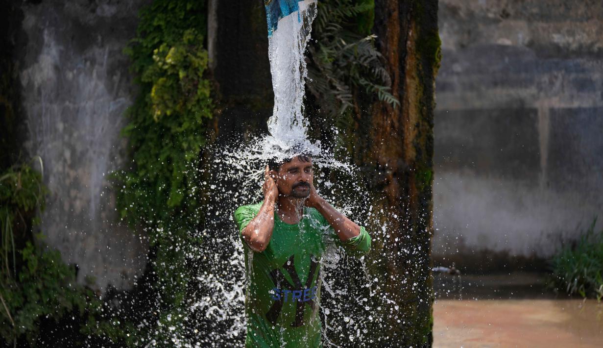 Seorang pria mandi menggunakan keran air pinggir jalan untuk mendinginkan diri di hari yang panas di pinggiran Jammu, India, Selasa 19 Mei 2026. (AP Photo/Channi Anand)