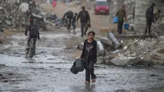 Seorang anak perempuan membawa dua ember kosong saat berjalan menuju tempat mengambil air di tengah hujan deras di kawasan Sheikh Radwan, Kota Gaza, Jumat 14 November 2025. Anak-anak di Gaza masih mengalami kekurangan air bersih. (AP Photo/Jehad Alshrafi)