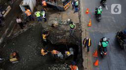 Pengendara melintas dekat perbaikan jalan ambles di Jalan Daan Mogot, Tangerang, Senin (13/1/2020). Amblesnya jalan penghubung ke Jakarta ini diduga karena adanya kebocoran pipa PDAM Tirta Kerta Raharja milik Pemkab Tangerang yang mengikis struktur tanah. (merdeka.com/Magang/Muhammad Fayyadh)