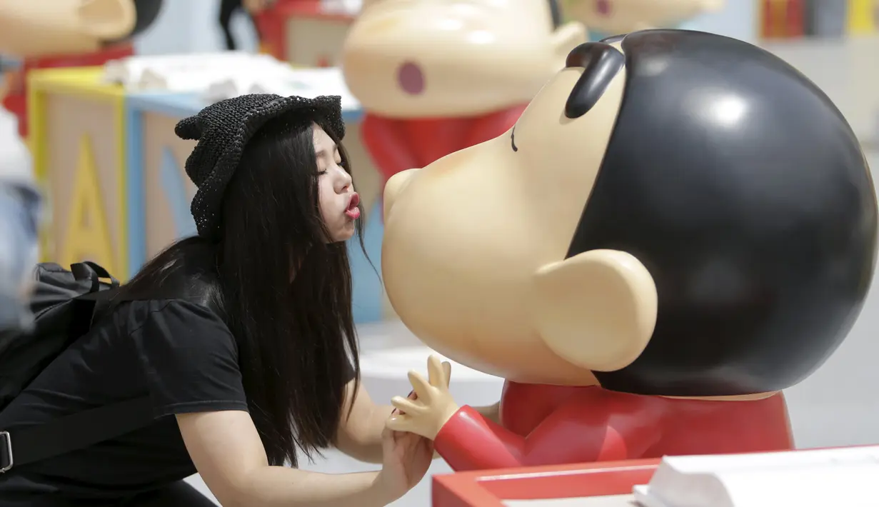 Seorang wanita berpose mengikuti gaya Crayon Shinchan saat berfoto di pameran Joy City, Beijing (5/5/2015). Lima puluh model karakter kartun Jepang dalam berbagai pose dan ekspresi dihadirkan dipameran tersebut. (REUTERS/Jason Lee)