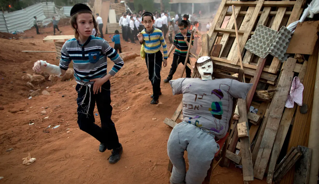 Anak-anak Yahudi Ultra Ortodoks menyusun kayu dan boneka "evil man" untuk dibakar saat perayaan hari Lag Ba'Omer di Bnei Brak, Israel (2/5). Tradisi ini merupakan peninggalan umat Yahudi sejak zaman Romawi. (AP Photo / Oded Balilty)