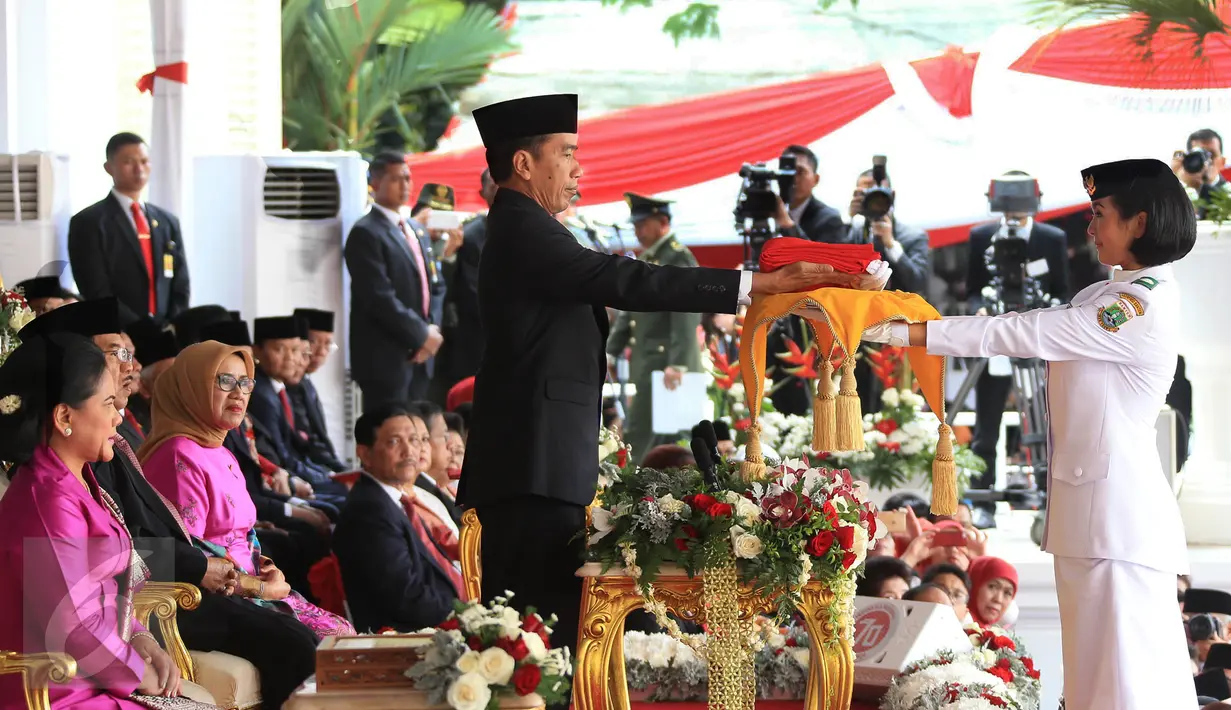 Presiden Jokowi (kiri) menyerahkan bendera Merah Putih kepada anggota Paskibraka Maria Felicia Gunawan saat Upacara Peringatan Detik-detik Proklamasi 17 Agustus di halaman Istana Merdeka, Jakarta, Senin (17/8/2015). (Liputan6.com/Faizal Fanani)