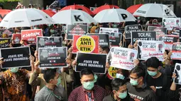 Pegawai KPK membawa poster saat menggelar aksi di Lobi Gedung KPK, Kuningan, Jakarta, Jumat (6/9/2019). Dalam aksi menolak revisi UU KPK tersebut, mereka mengenakan baju serba hitam lengkap dengan masker penutup mulut dan membawa payung. (merdeka.com/Dwi Narwoko)