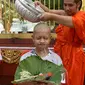 Biksu mengguyur kepala salah satu anak, yang diselamatkan dari gua di Thailand, pada upacara pentahbisan di Kuil Wat Phra That Doi Wao, Chiang Rai, Selasa (24/7). Sebanyak 11 remaja menjalani ritual menjadi biksu. (Panumas Sanguanwong/THAI NEWS PIX/AFP)