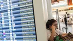 Seorang wanita beristirahat di samping papan informasi penerbangan di Terminal Internasional Bandara Haneda setelah penerbangan dibatalkan atau ditunda karena badai tropis Jangmi di Tokyo, Jepang, Rabu 3 Juni 2026. (Andrew CAALLERO-REYNOLDS/AFP)