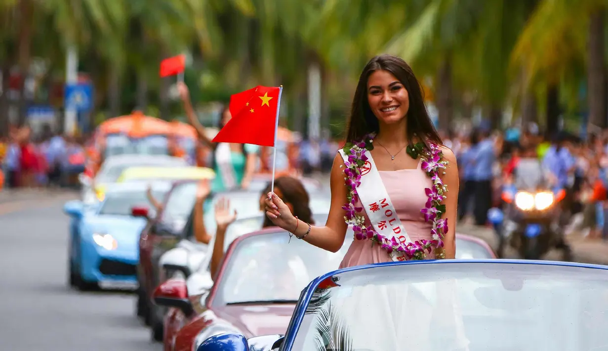 Kontestan Miss World dari Moldova tersenyum sambil membawa bendera China saat mengikuti pawai menggunakan supercar di Sanya, Provinsi Hainan, China, (7/11). Pawai ini membuka kontes kecantikan Miss World ke-67. (AFP Photo/Str/China Out)