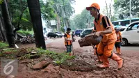 Petugas PPSU atau yang lebih dikenal dengan sebutan Pasukan Oranye membersihkan sendimen tanah merah yang longsor ke jalan Galunggung, Jakarta, Selasa (30/8/2016). (Liputan6.com/Yoppy Renato)